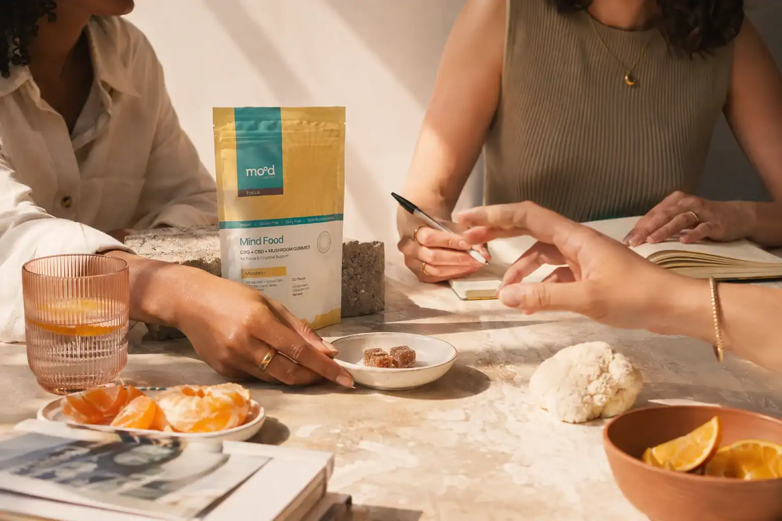 אריזת Mind Food על שולחן משותף, לצד מחברת, קלמנטינות ופטריית רעמת האריה